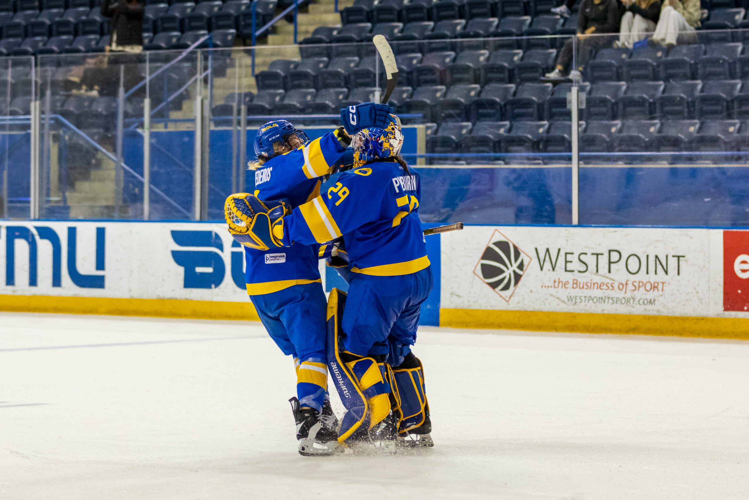 Two TMU Bold women's hockey players embracing each other at the Mattamy Athletic centre