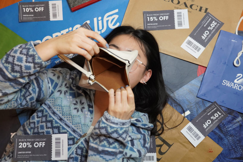 Image of someone covering their face with an empty wallet surrounded by a collage of different company bags and coupons.