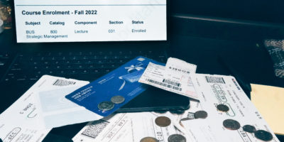 Image of travel tickets, foreign money and a computer with tuition costs open on the screen.