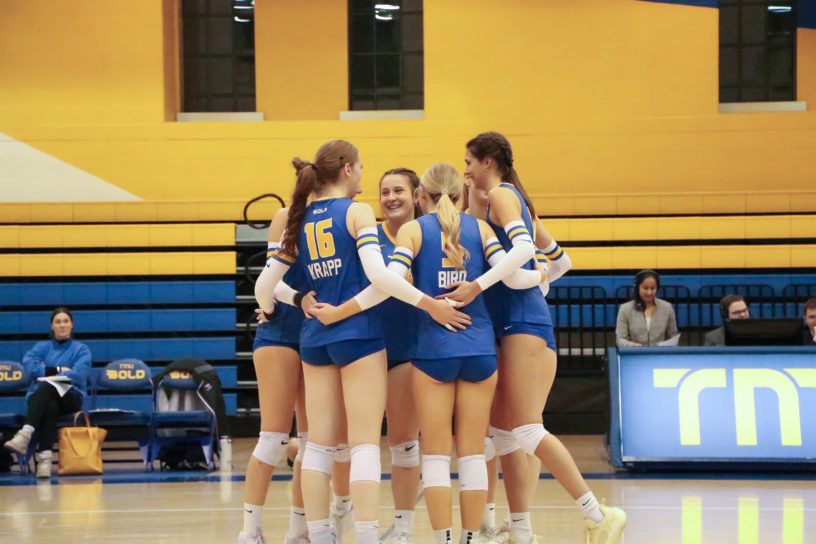 TMU bold women's volleyball team in a huddle during a stoppage of play