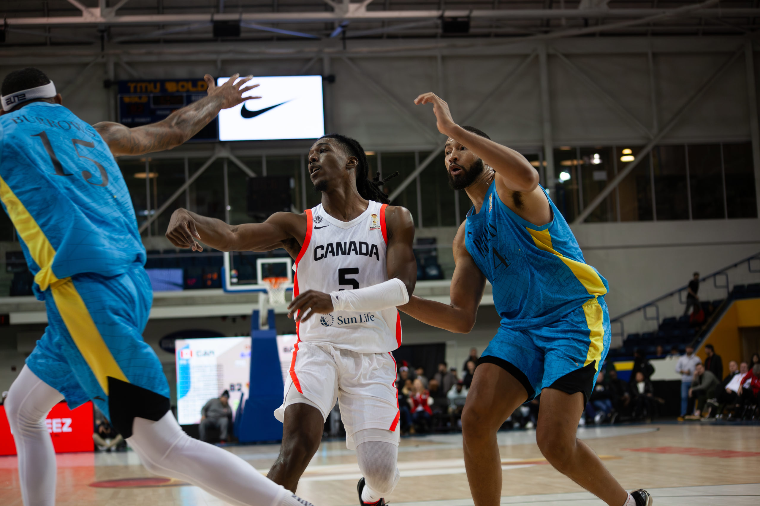 Marcus Carr passing the ball being guarded by two Bohemian players