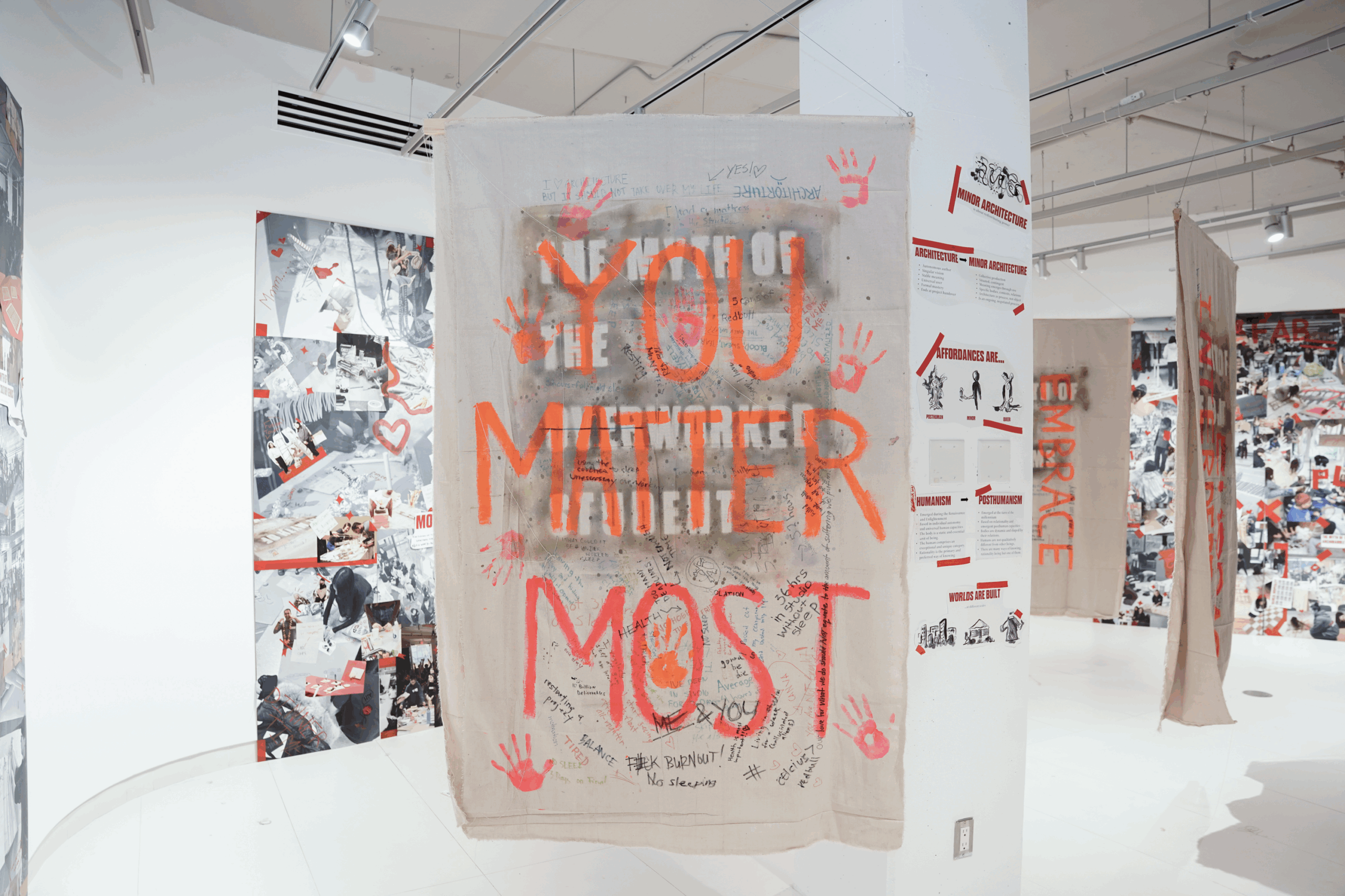 A large white sheet hands in the middle of an art gallery with the phrase 'You Matter Most' painted in orange over it.