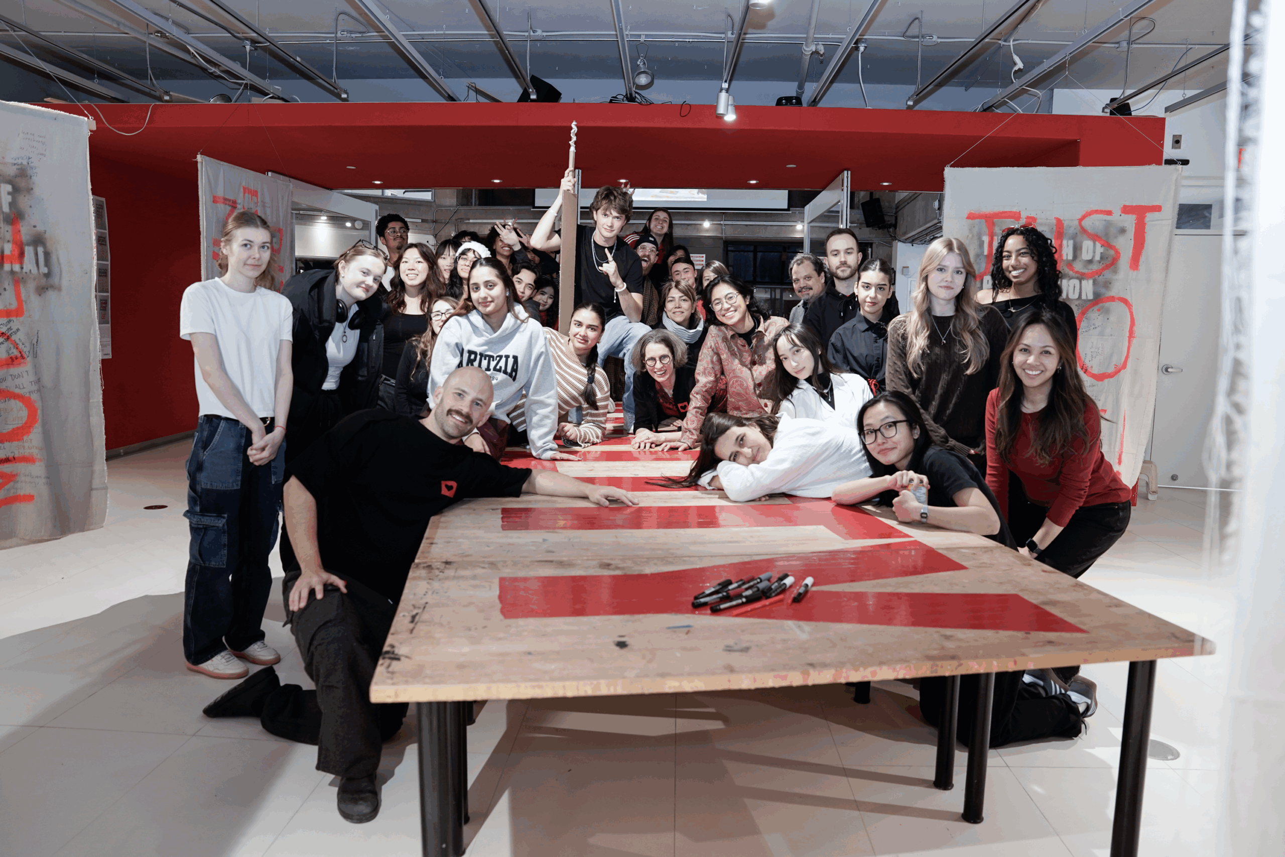 A large group of people pose for a photo in the middle of an art gallery.