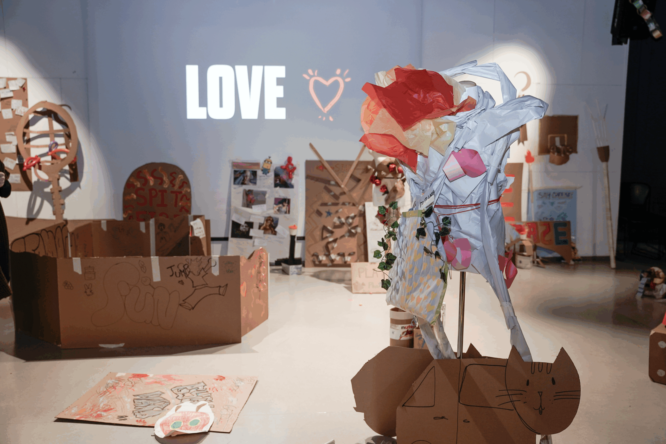 An abstract, mannequin-like sculpture stands in the middle of an art gallery.