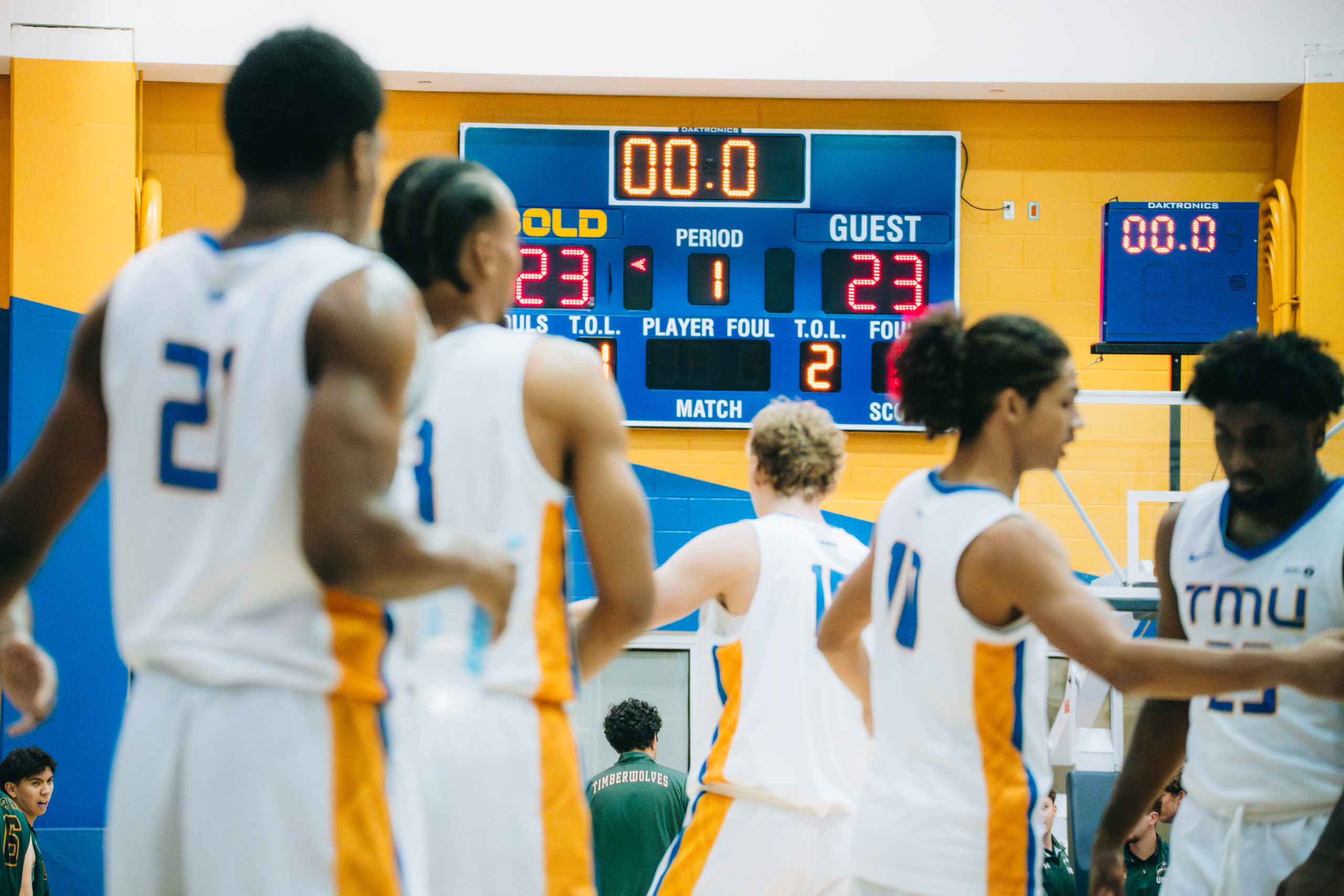 TMU men's basketball team surrounding the bench at the end of a quarter