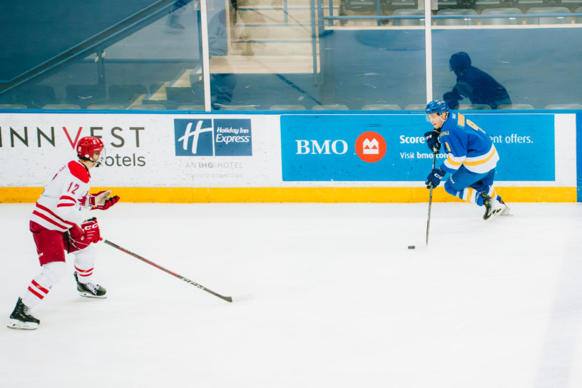 A TMU player maintains possession of the puck while watching a York defender