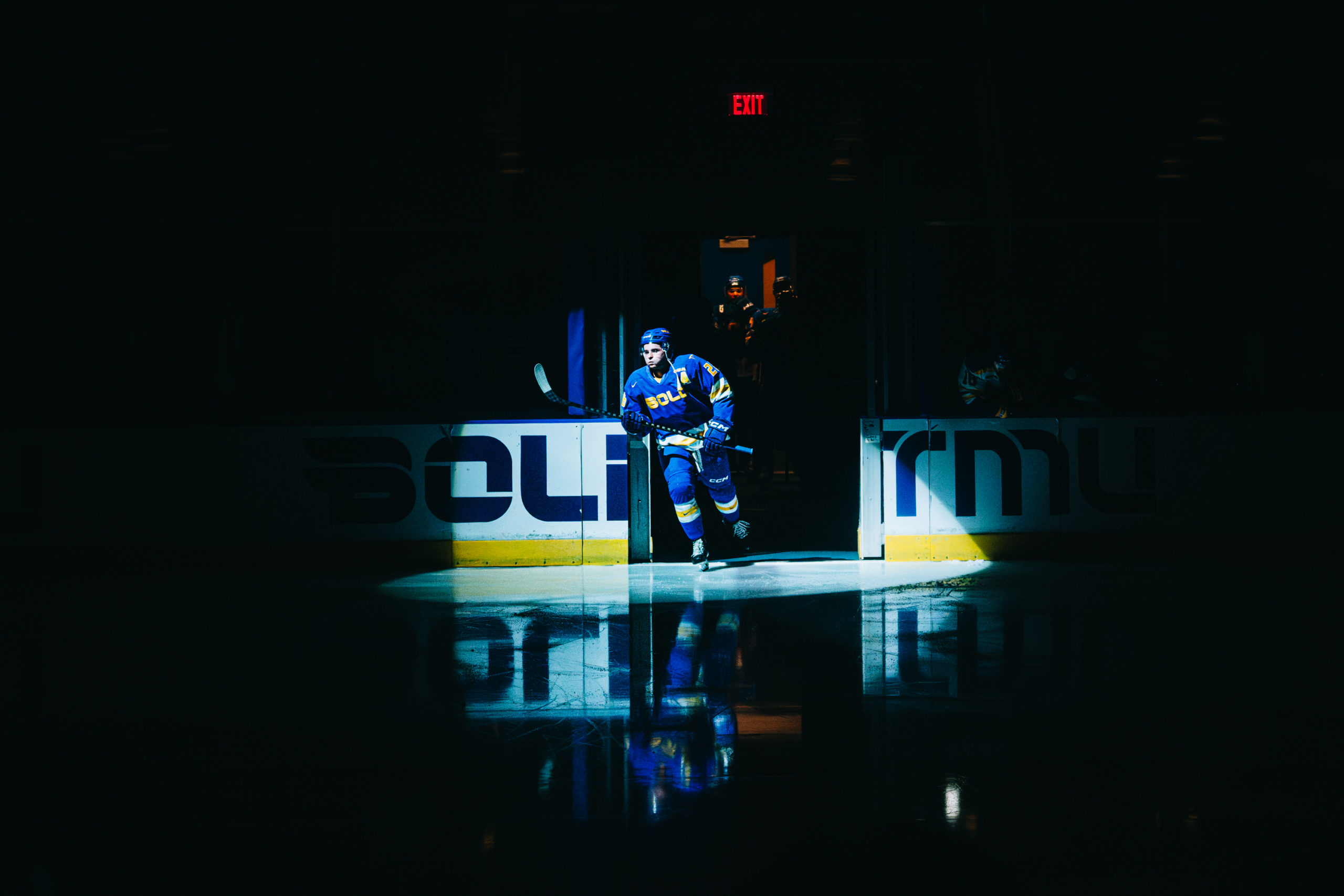 TMU Bold men's hockey player enters the ice highlighted by a spotlight at the Mattamy Athletic Centre