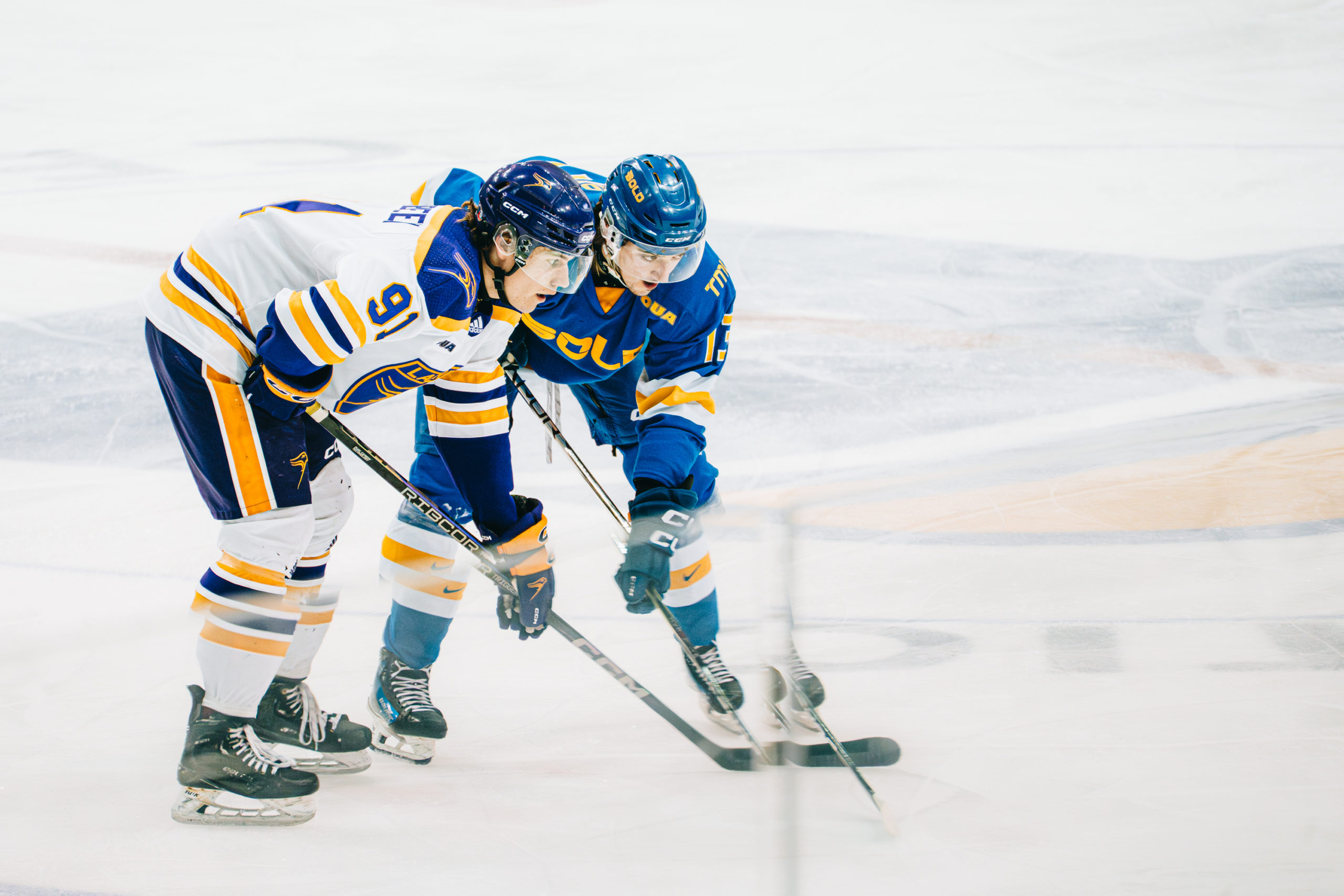 A TMU men's hockey player stands beside s Laurier player in a defensive stance at the Mattamy Athletic Centre
