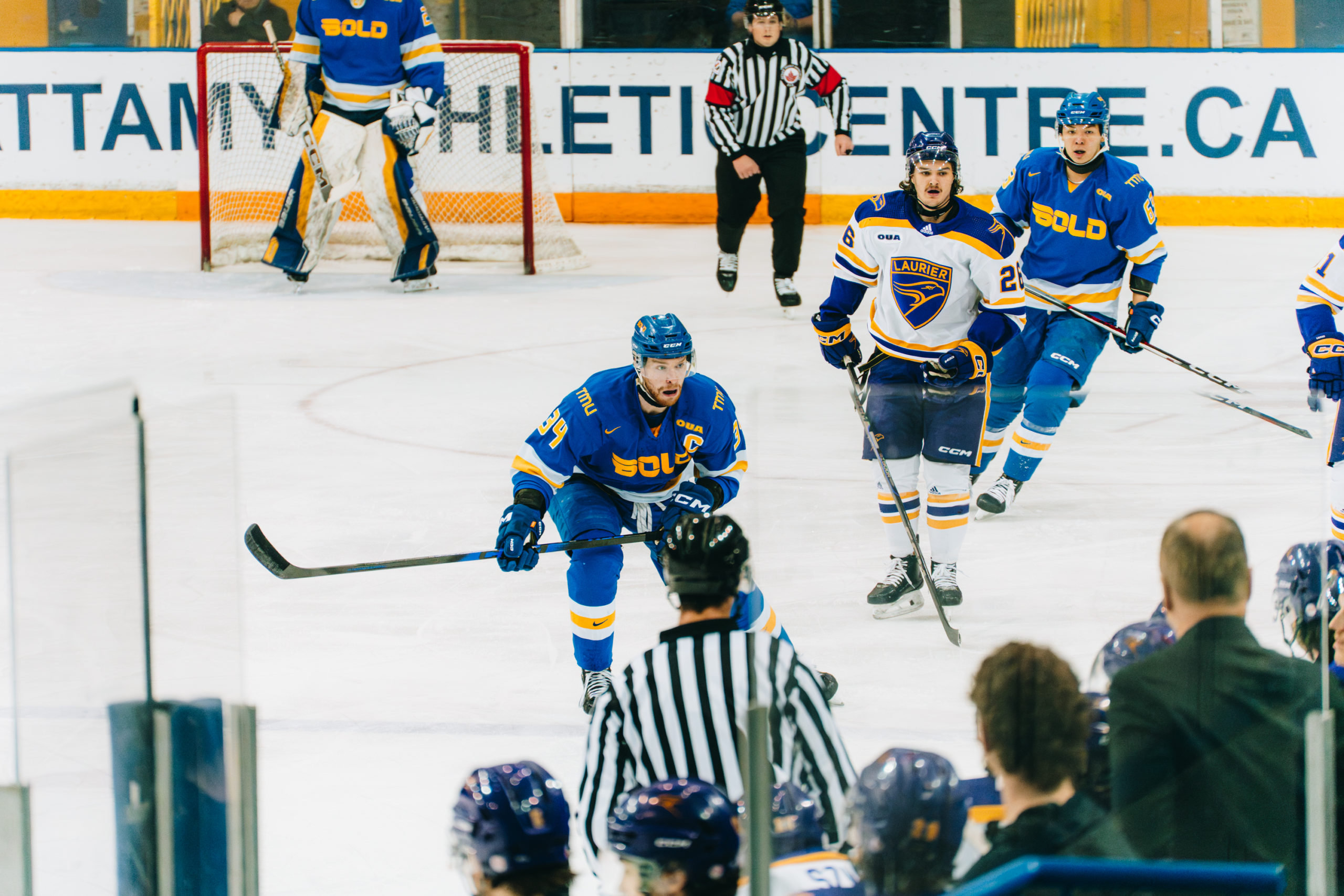 TMU Bold men's hockey player in a defensive stance near the the middle of the ice at the Mattamy Athletic Centre