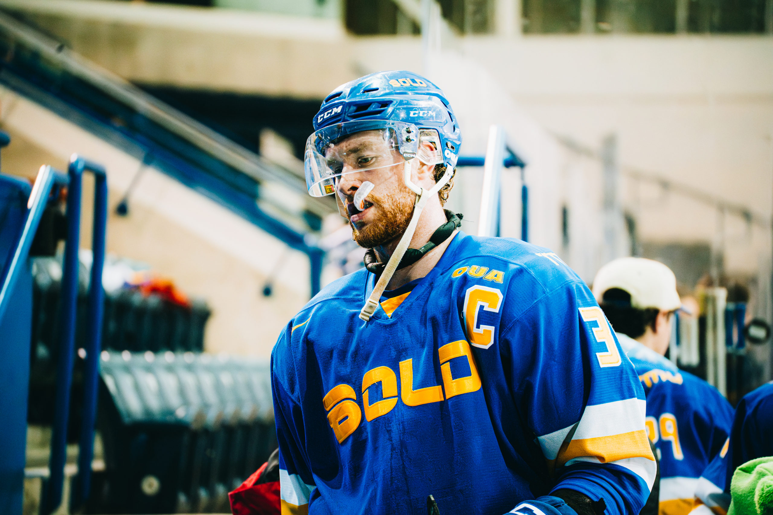 TMU Bold men's hockey player biting down on his mouth guard walking into the players' tunnel at the Mattamy Athletic Centre