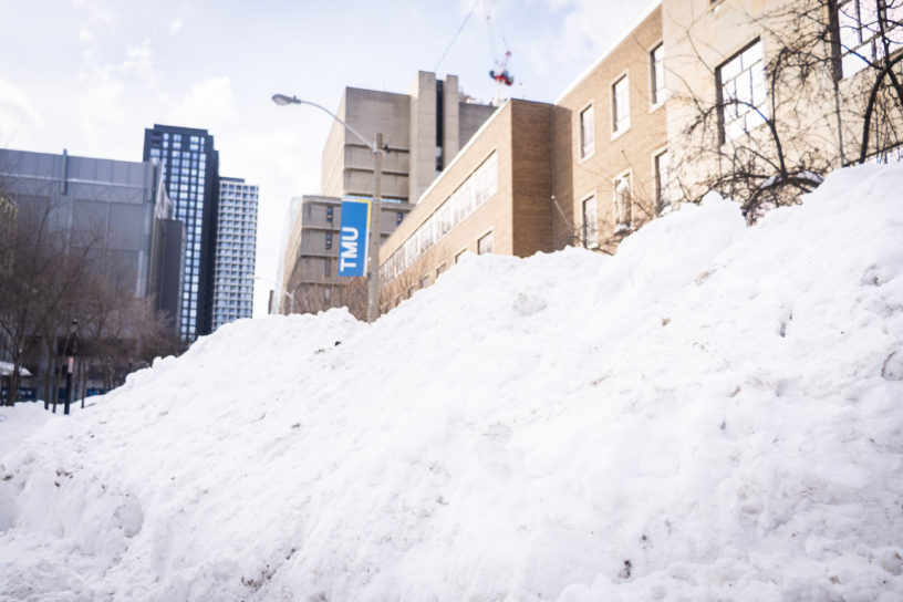 Photo of a snowbank with a banner that reads "TMU" in the background.