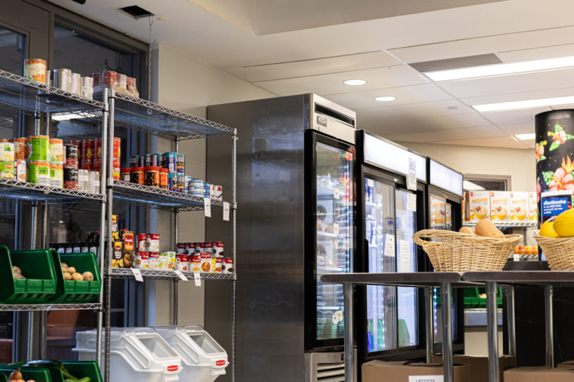 Image of a room with cans of food on the shelves and four fridges along the wall.