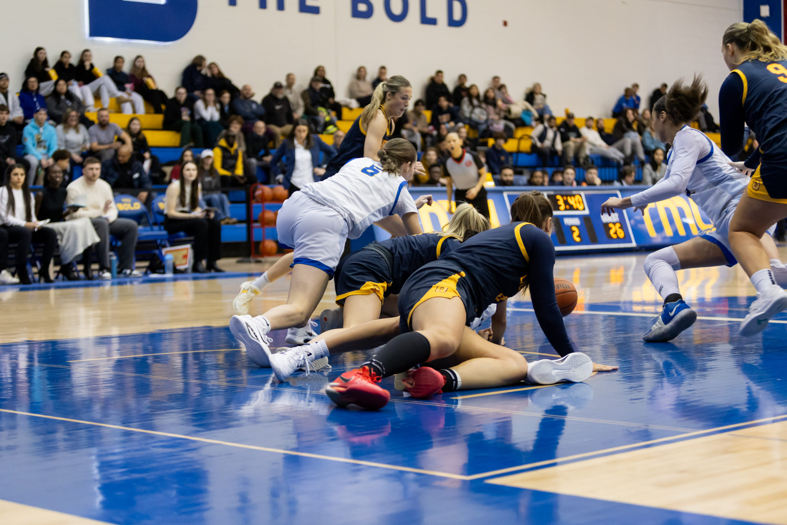 TMU and Queen's fight for possession while sprawled on the ground