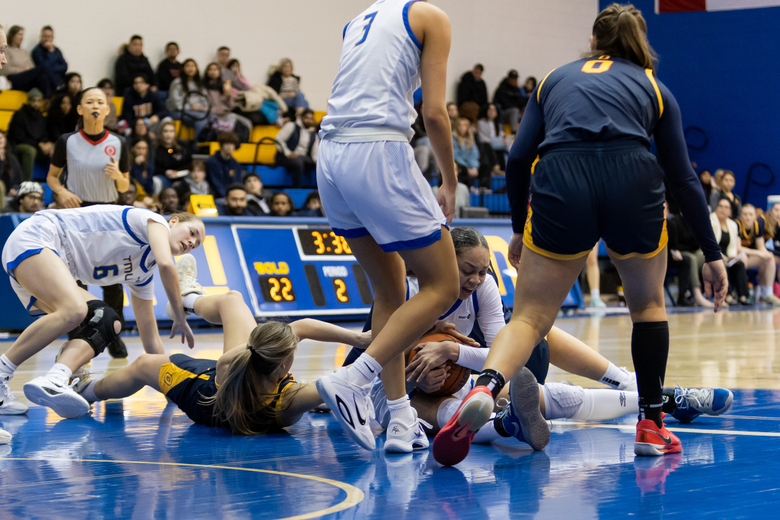 TMU and Queen's fight for possession while sprawled on the ground