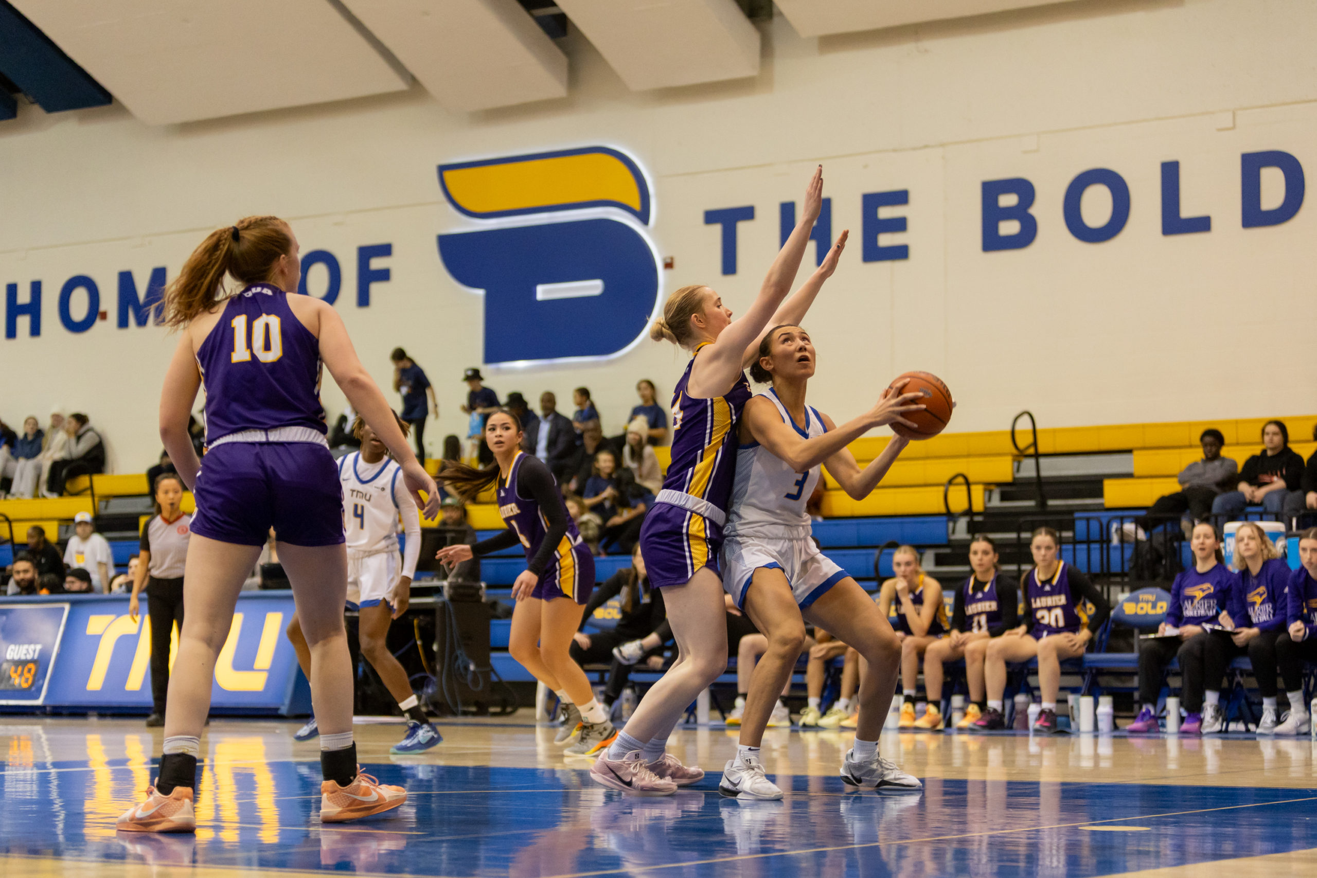 Hailey Franco DeRyck attempts a basket amidst Laurier defenders