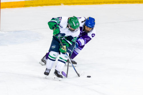 A TMU women’s hockey player and a Nipissing player fight for possession of the puck at the Mattamy Athletic Centre