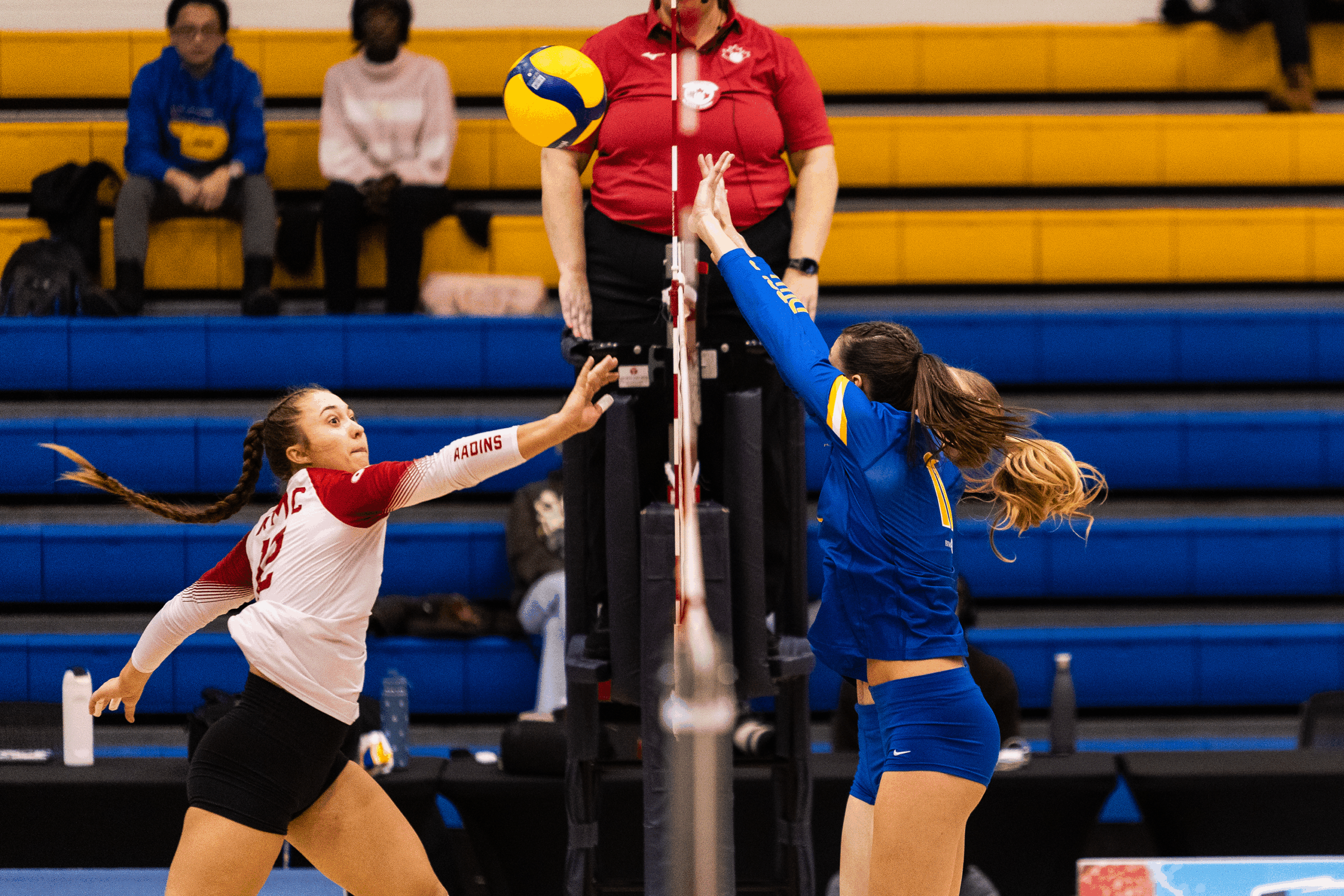 An RMC player prepares to send the ball over to TMU's court, as TMU defenders prepare to block