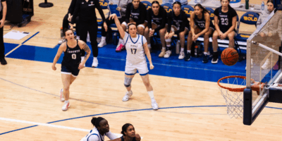 A TMU basketball player makes a shot at U of T's net