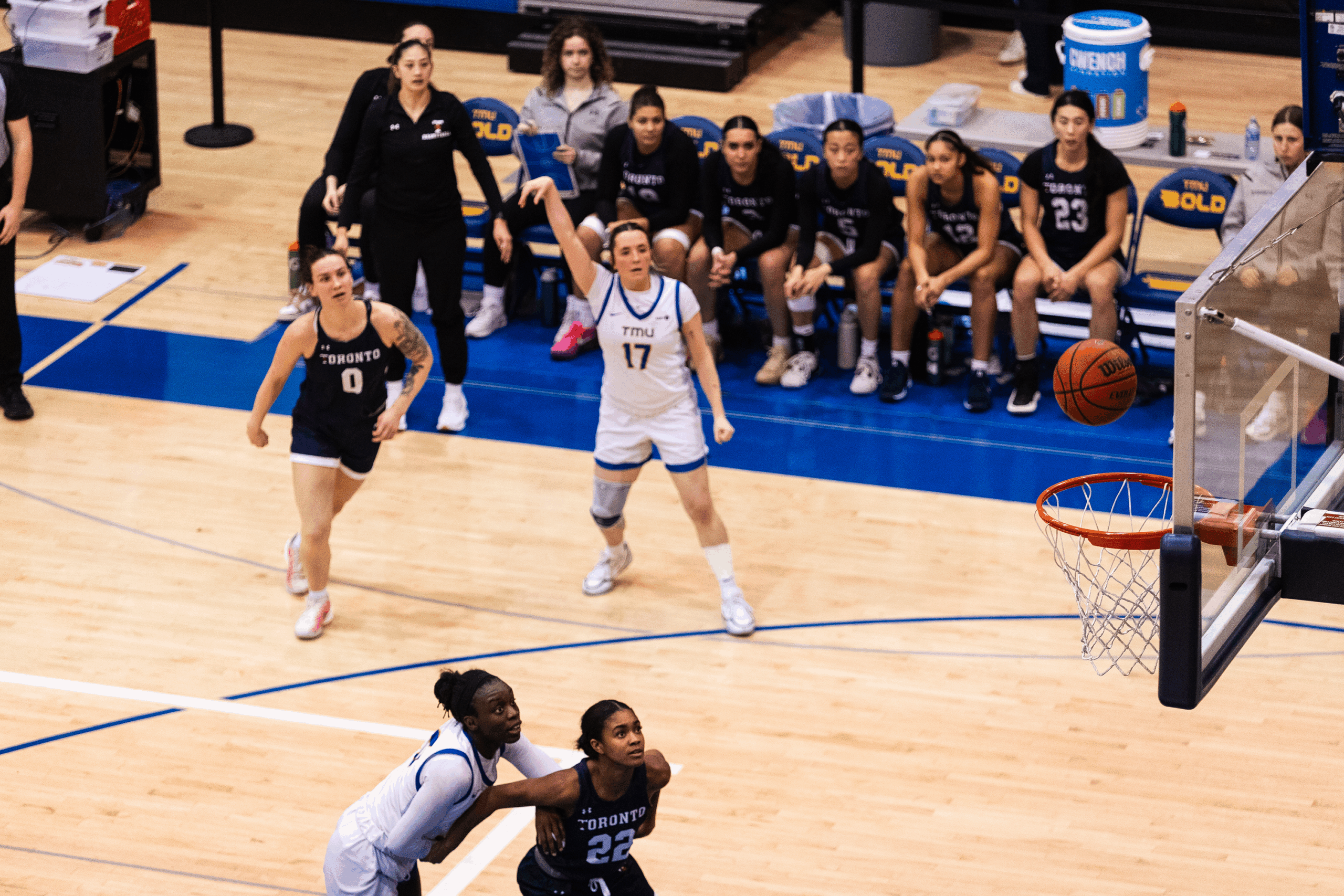 A TMU basketball player makes a shot at U of T's net