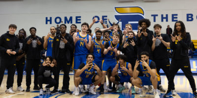 TMU bold men's basketball team comes together for a group photo after a win against Brock in the 2026 OUA playoffs
