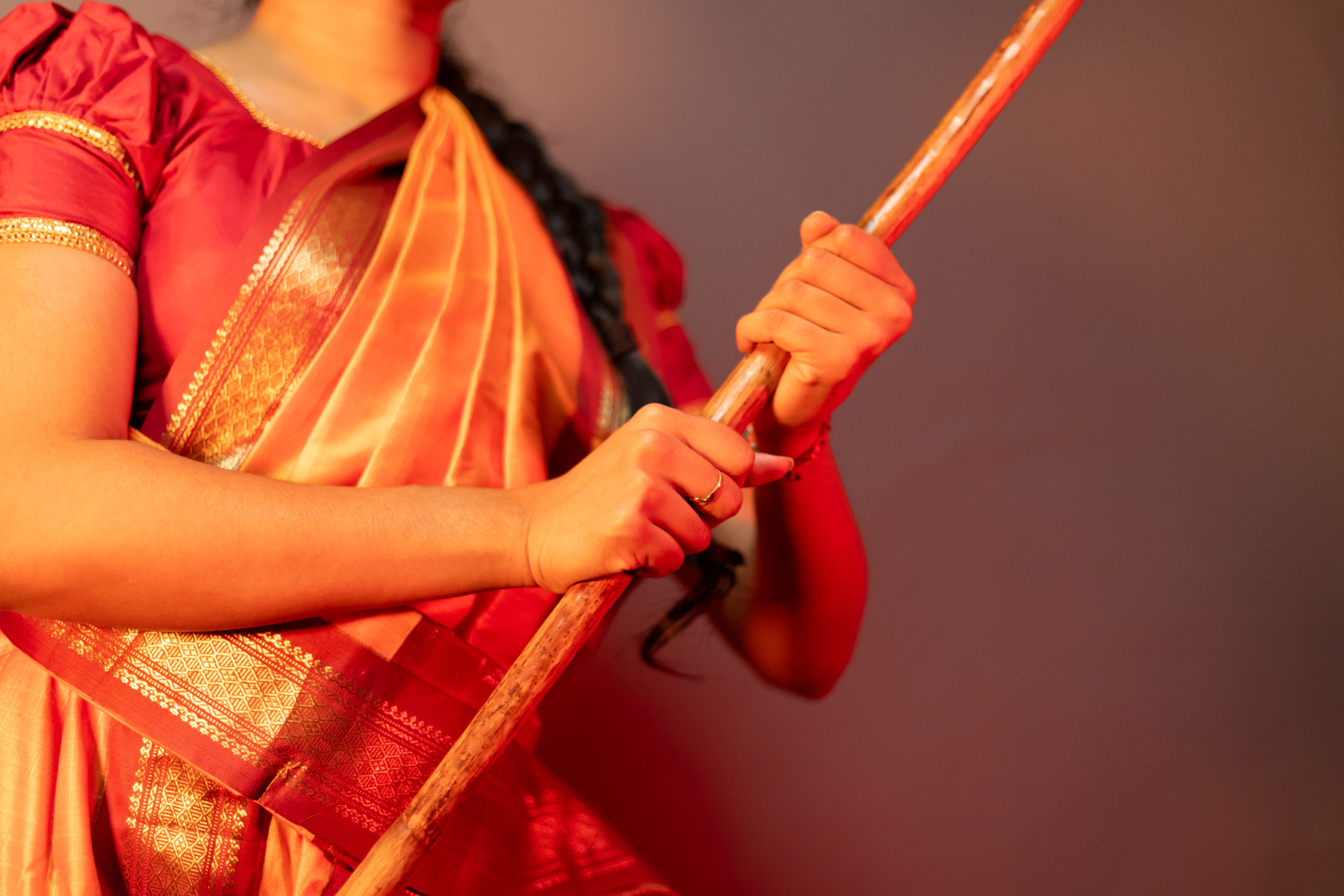 A close up of Aishvini Partheepan holding her silambam staff with two hands.