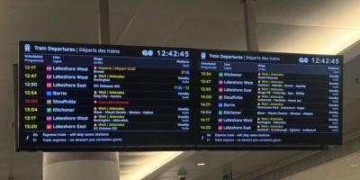 An image of a monitor hanging in the middle of Union Station in Toronto, displaying train times. Most trains are delayed or cancelled.