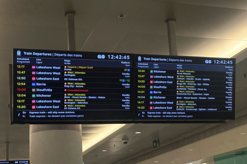 An image of a monitor hanging in the middle of Union Station in Toronto, displaying train times. Most trains are delayed or cancelled.