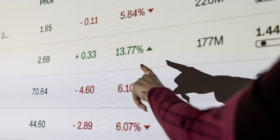 Someone pointing at a projection of numbers and percentages on a wall.