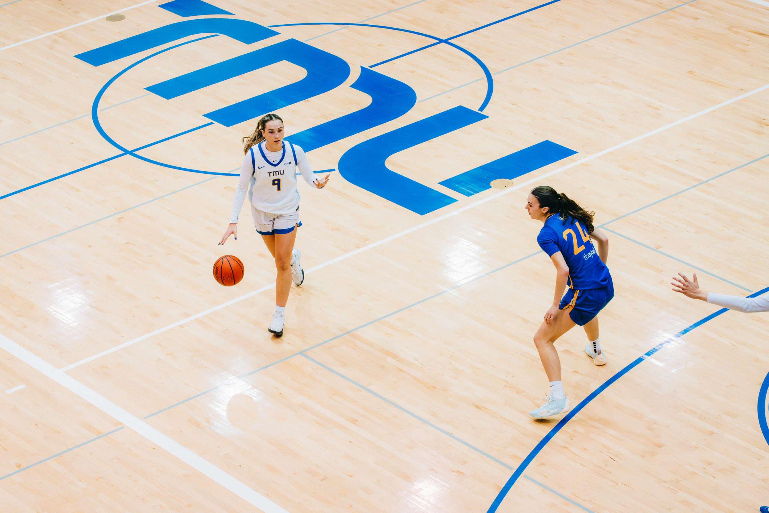 A TMU player maintains possession as she tries to avoid a Lakehead defender