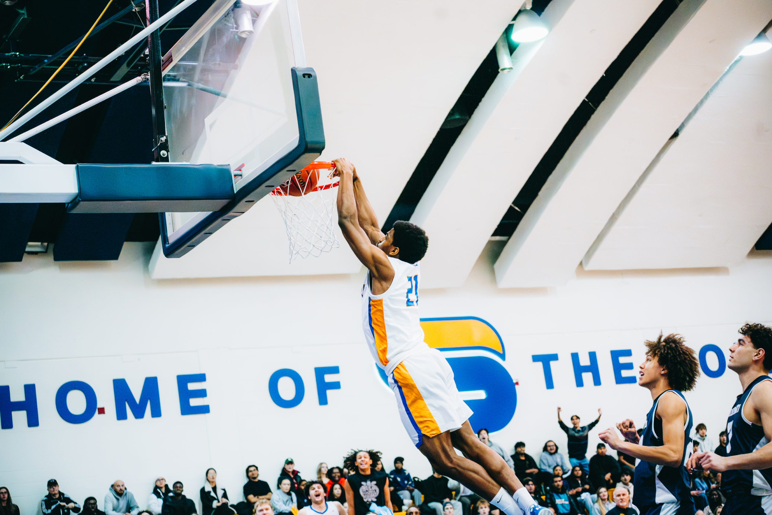 A TMU basketball player makes a dunk in U of T's basket