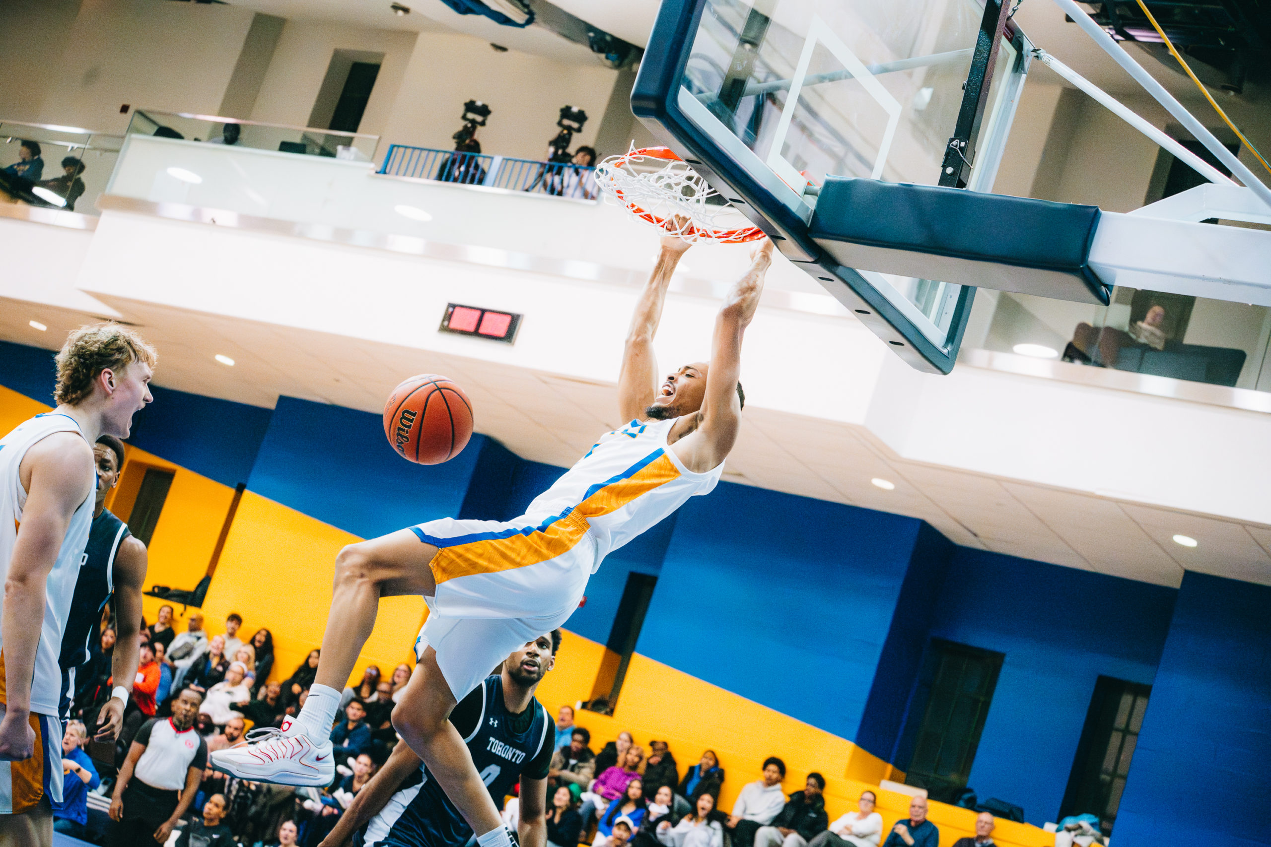 A TMU basketball player makes a slam dunk against U of T