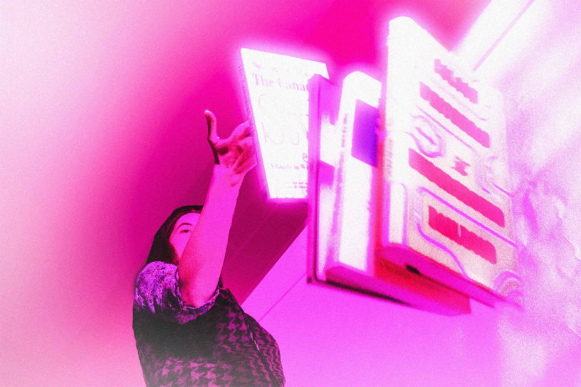 A person throws books onto the floor, an ominous pink light is casted over the image.