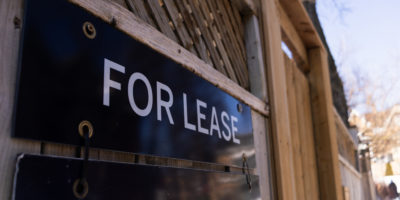 A for lease sign nailed to a wooden gate.
