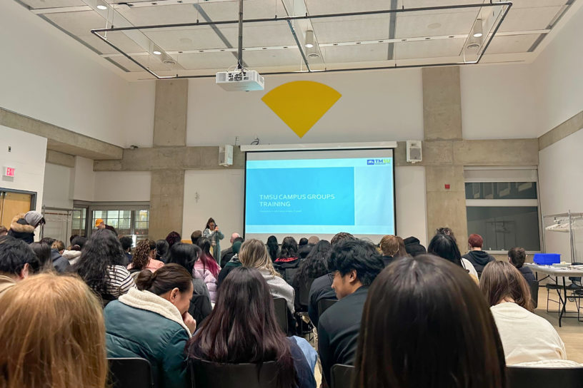Several people sitting on chairs in a room with a screen that reads "TMSU Campus Groups Training"