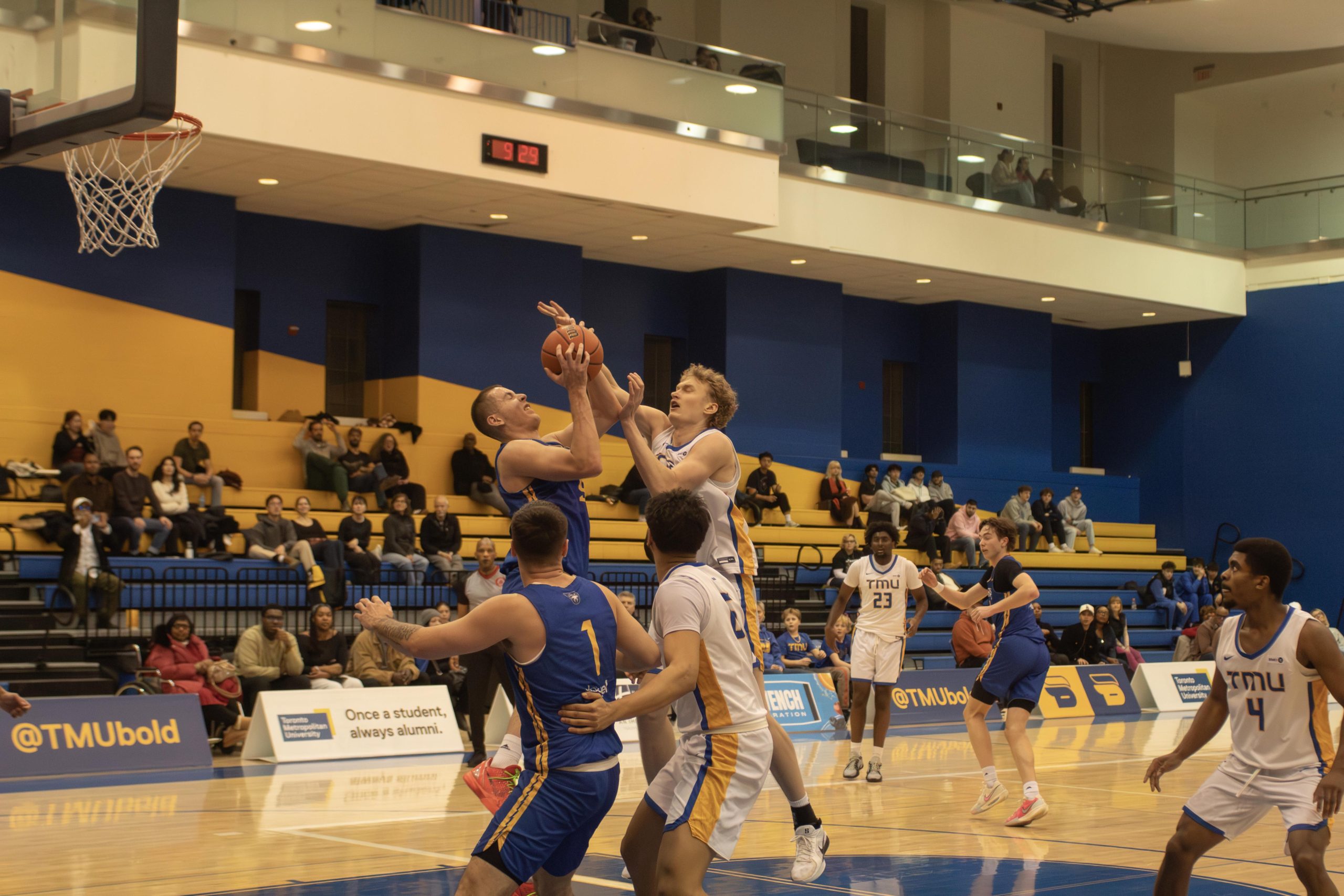 Lakehead and TMU men's basketball players attempt to rebound the ball at the Mattamy Athletic Centre