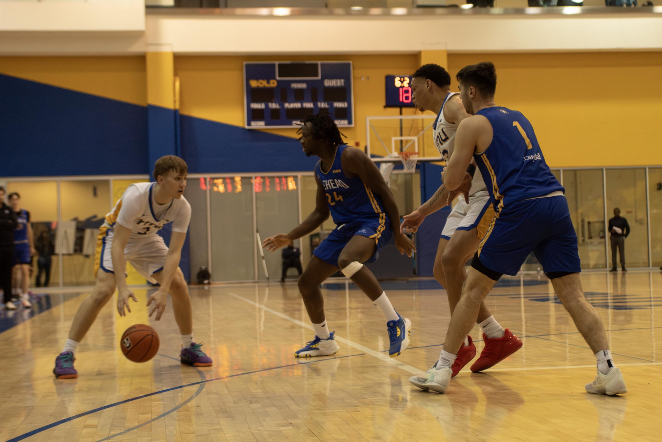 TMU men's basketball player passes to teammate in the post at the Mattamy Athletic Centre