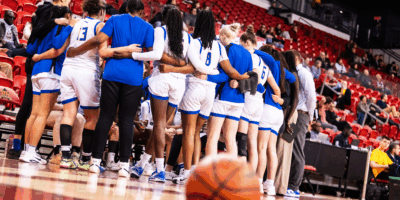 A basketball sits on the court as TMU huddles around their bench