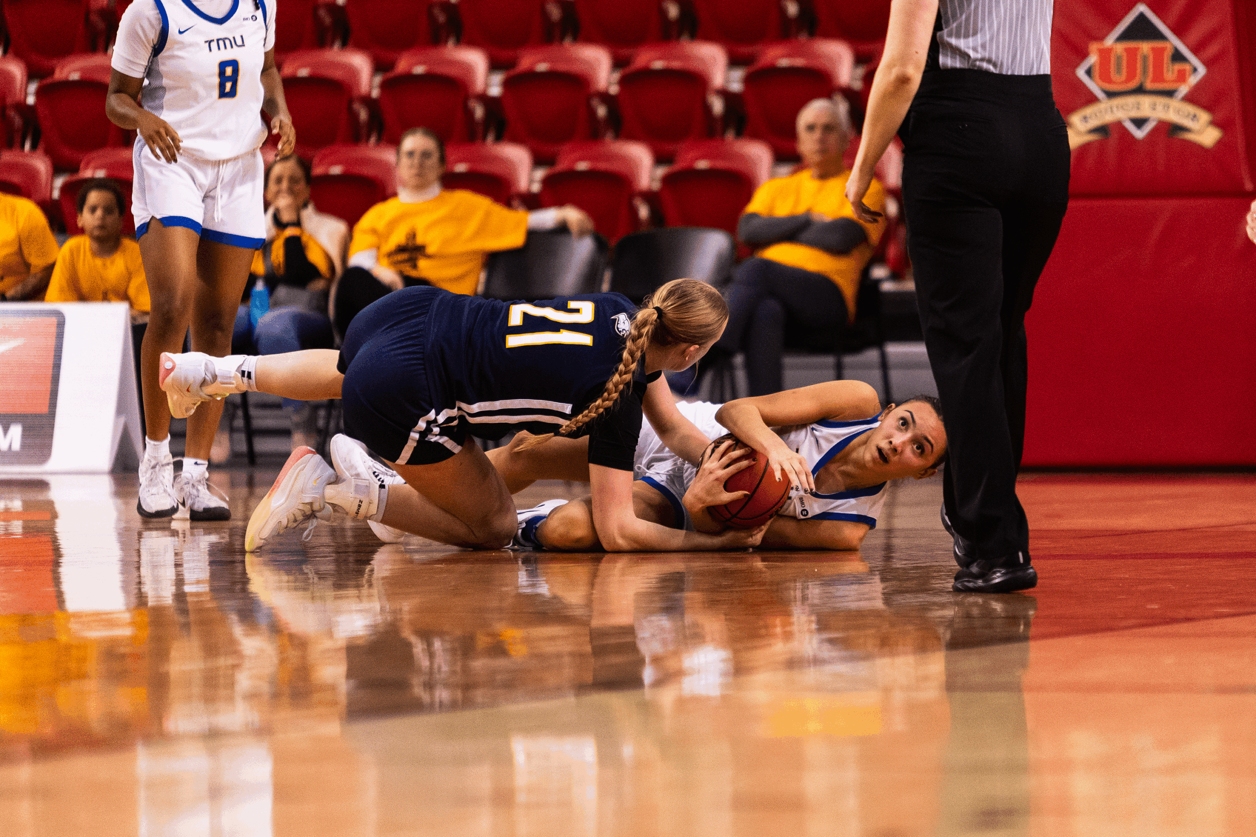 Hailey Franco DeRyck maintains possession while on the ground amidst UBC opponents