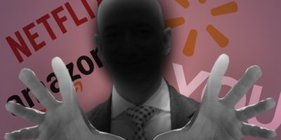 An image of a bald headed man with a shadow cast over him and arms outstretched, with various logos in the background.