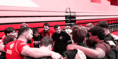 The brazilian jiu jitsu team in a huddle with a red hue over them.