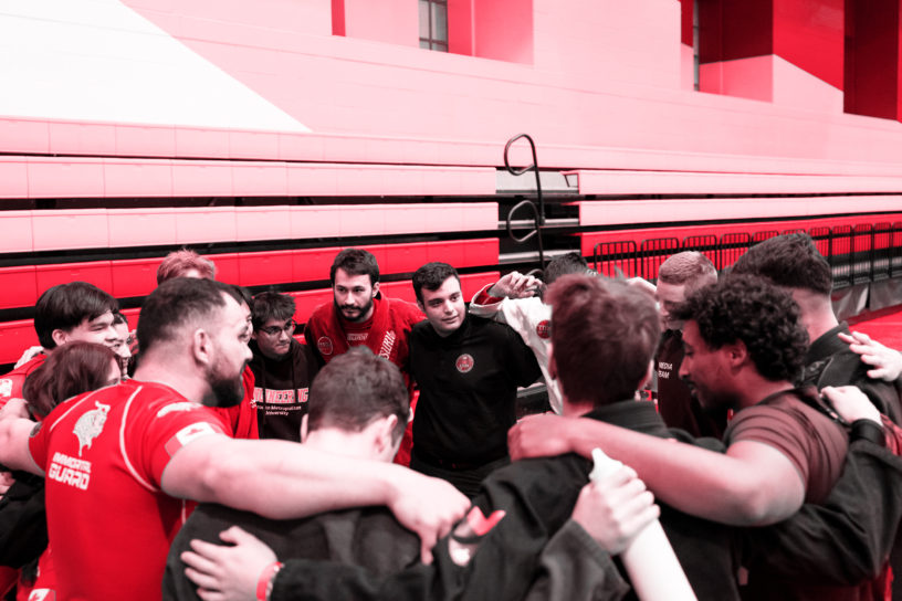 The brazilian jiu jitsu team in a huddle with a red hue over them.