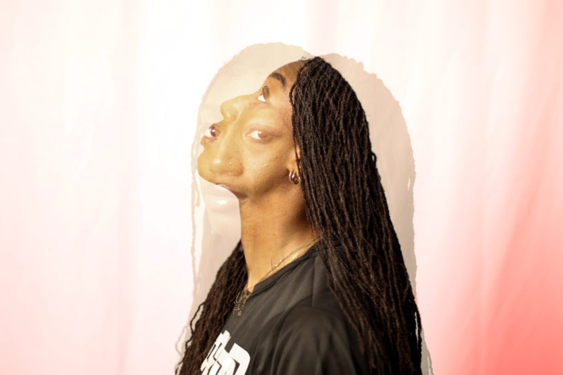 A double exposure image of a woman looking up and looking towards the camera in front of a pink and while background.