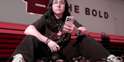 Chrysoula Dimitrakopoulos sitting on a basketball court with a bunch of cameras below her.