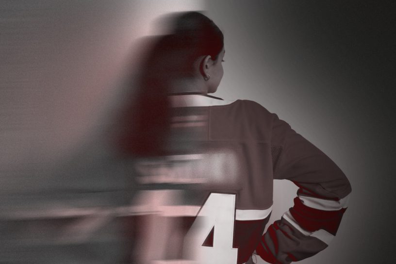 An image of the back of a woman wearing a hockey jersey, with half of the image blurred.