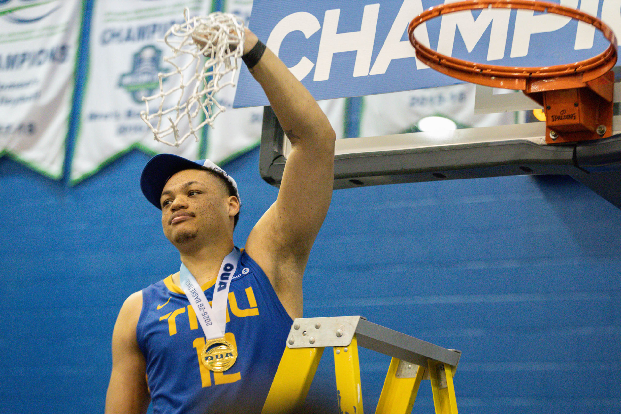 Aaron Rhooms cutting the net at the at the Mattamy Athletic Centre