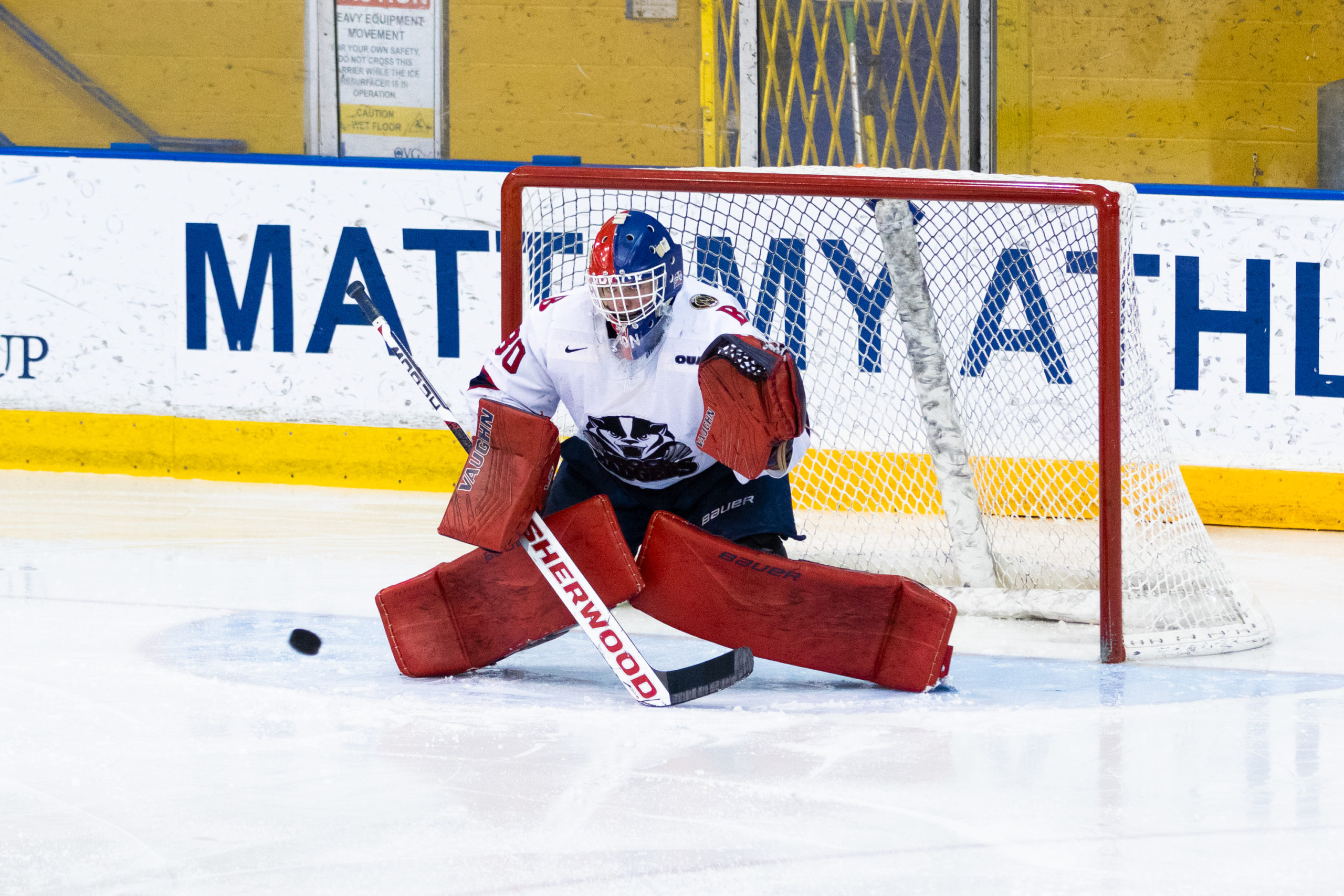 The puck slides to the right of a Brock goaltender in front of his net