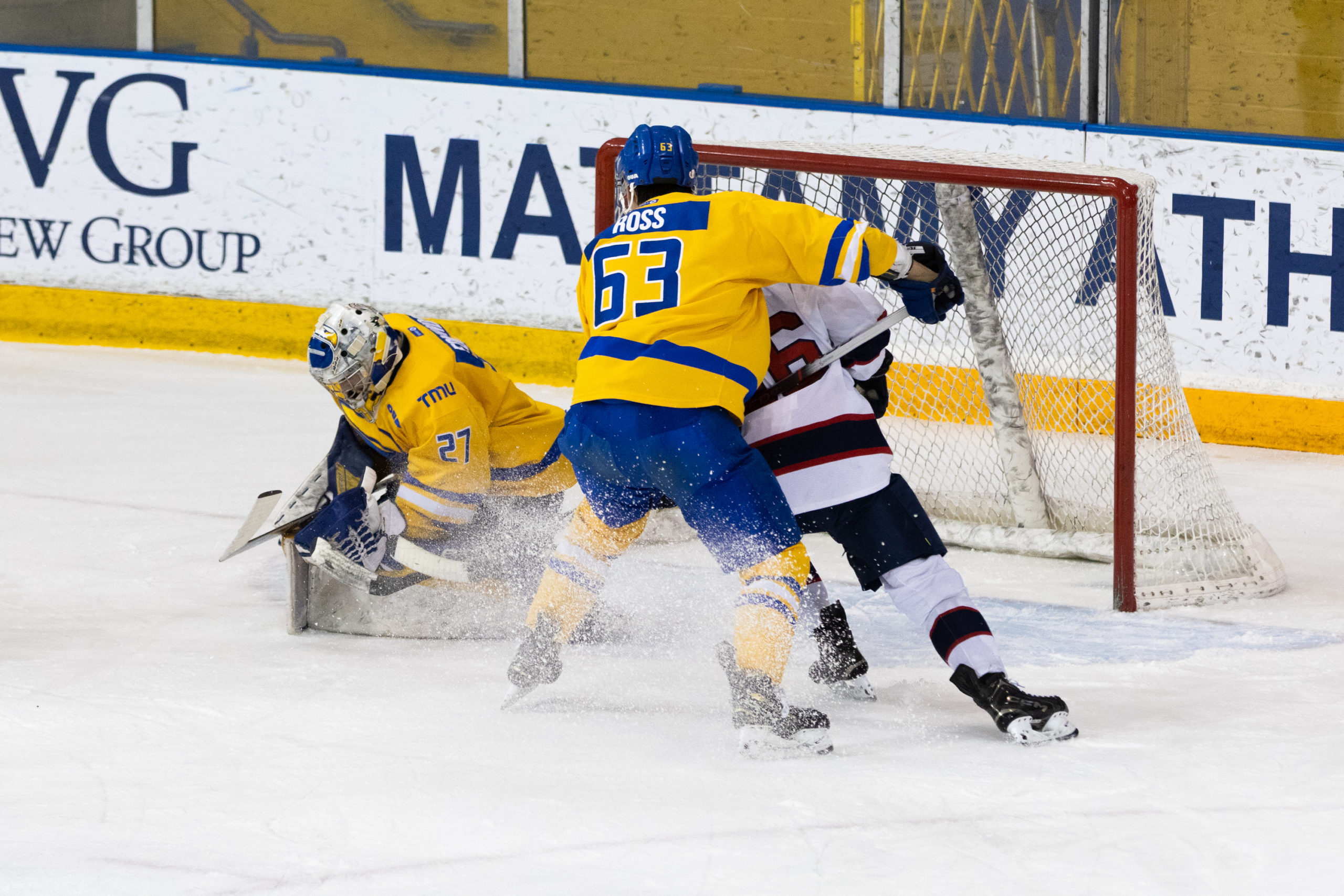 A TMU defender grabs onto a Brock opponent in front of TMU's net
