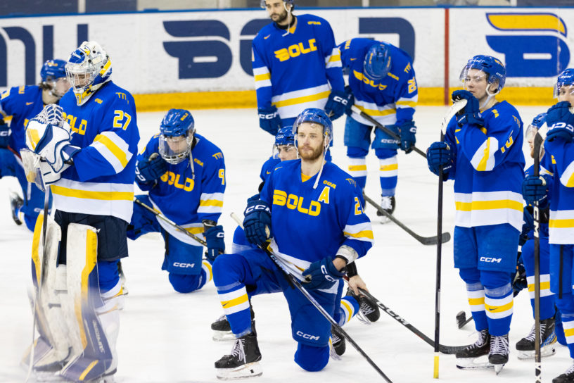 TMU, kneeling on the ice, accepts their bronze medal match defeat