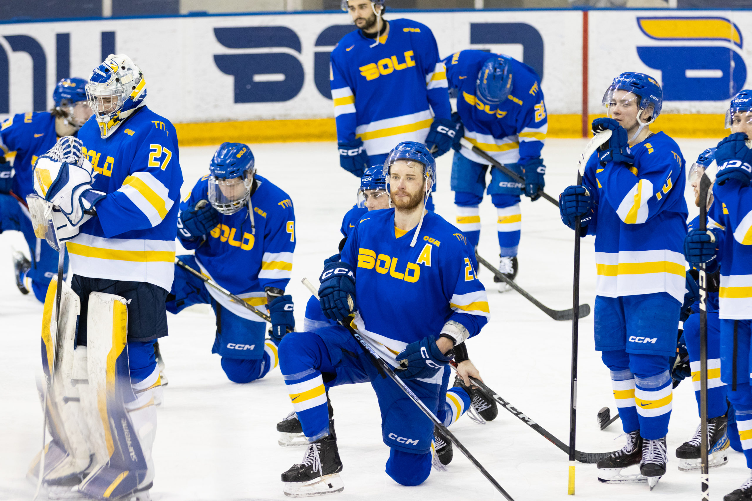TMU, kneeling on the ice, accepts their bronze medal match defeat