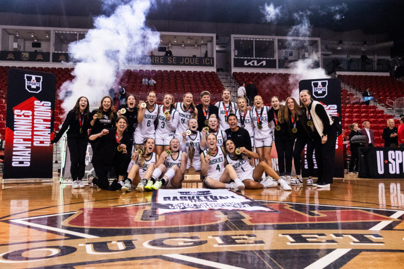 The University of Saskatchewan Huskies pose for a photo with their championship banner and trophy